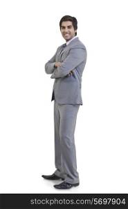Full length portrait of young businessman with arms crossed standing against white background