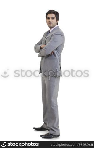 Full length portrait of young businessman with arms crossed standing against white background