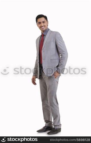 Full length portrait of young businessman with hand in pocket standing against white background