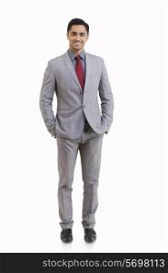 Full length portrait of young businessman with hands in pockets isolated over white background