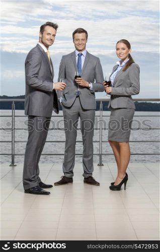 Full length portrait of young businesspeople holding wineglasses on terrace