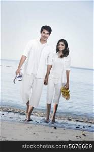 Full length portrait of young couple walking together on beach