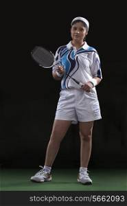 Full length portrait of young female player holding badminton racket isolated over black background