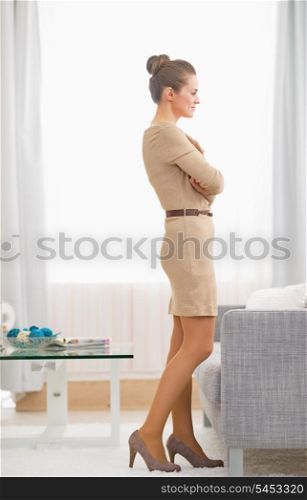 Full length portrait of young housewife standing in living room