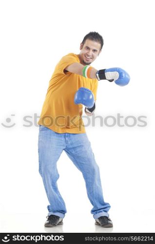 Full length portrait of young man in casuals wearing boxing gloves over white background