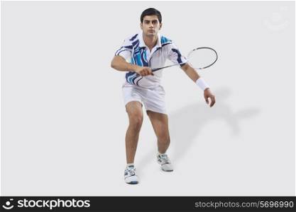 Full length portrait of young man playing badminton isolated over white background