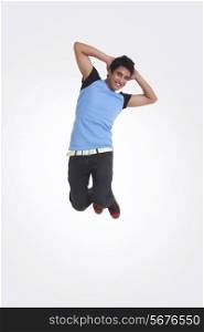 Full length portrait of young man with hands behind head jumping over white background