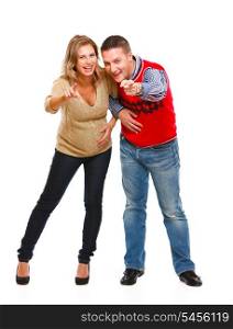 Full length portrait of young pregnant woman with husband pointing in camera on white background &#xA;