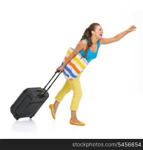 Full length portrait of young tourist woman with wheel bag catching taxi