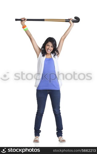 Full length portrait of young woman holding up hockey stick over white background