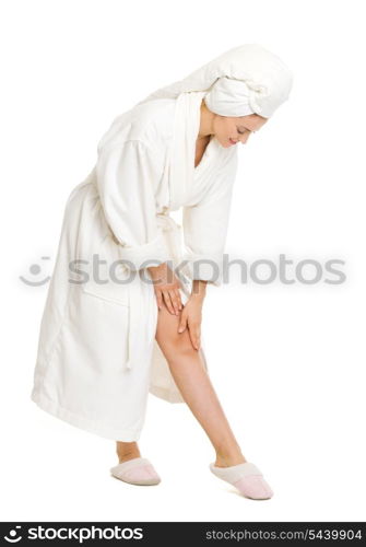 Full length portrait of young woman in bathrobe checking leg