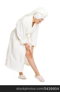 Full length portrait of young woman in bathrobe checking leg