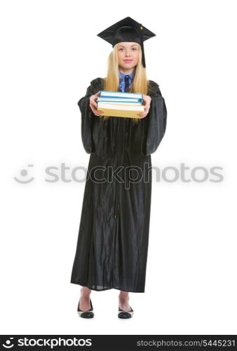 Full length portrait of young woman in graduation gown giving books