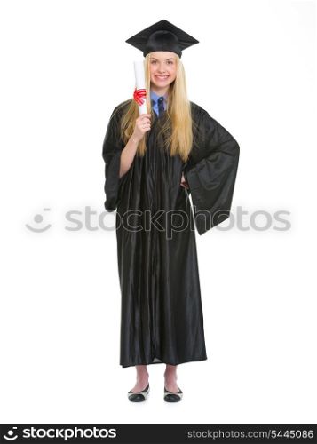 Full length portrait of young woman in graduation gown showing diploma