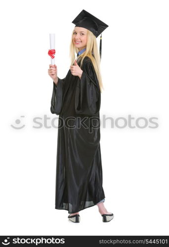 Full length portrait of young woman in graduation gown showing diploma and thumbs up
