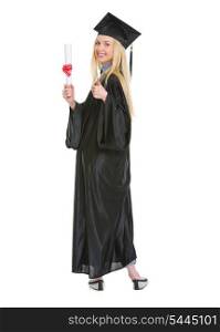 Full length portrait of young woman in graduation gown showing diploma and thumbs up