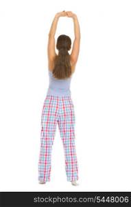Full length portrait of young woman in pajamas stretching. Rear view