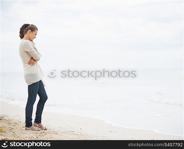 Full length portrait of young woman in sweater on beach