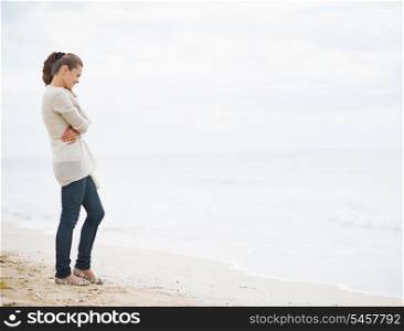 Full length portrait of young woman in sweater on beach