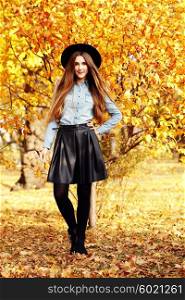 Full-length portrait young elegant woman wearing denim shirt, leather skirt, black coat and hat. Fashion outdoors shot, street style concept, autumn color