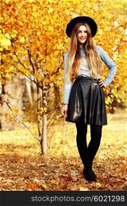 Full-length portrait young elegant woman wearing denim shirt, leather skirt, black coat and hat. Fashion outdoors shot, street style concept, autumn color