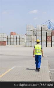 Full-length rear view of male worker walking in shipping yard