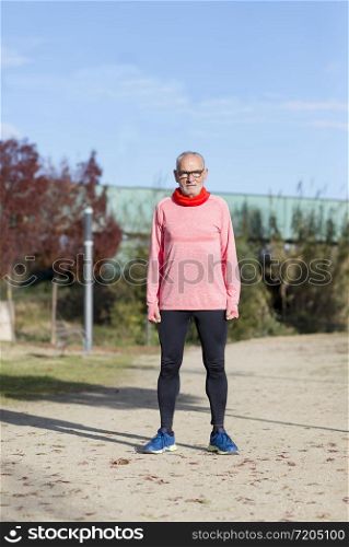 Full length Runner in rose sportswear standing at the park
