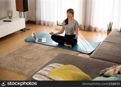 Full length shot of a woman doing yoga at home
