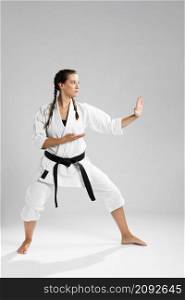 full length shot woman with black belt kimono practicing karate