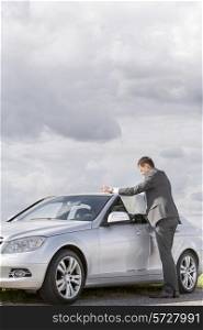 Full length side view of businessman reading map by car at countryside