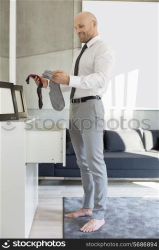 Full length side view of businessman selecting socks at home
