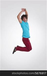 Full length side view of excited young man jumping over white background