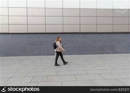 Full length side view portrait of trendy caucasian woman walking outdoors