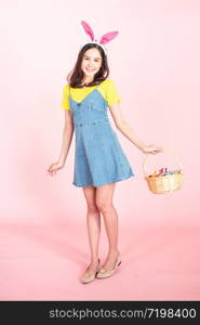 full length studio shot of asian beauty happy young woman wearing bunny ears and holding colorful Easter egg in wood basket with lovely smile and colorful decor costume isolated on pastel backgrounds.