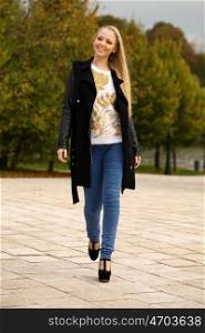 Full length, walking happy blonde woman in autumn park