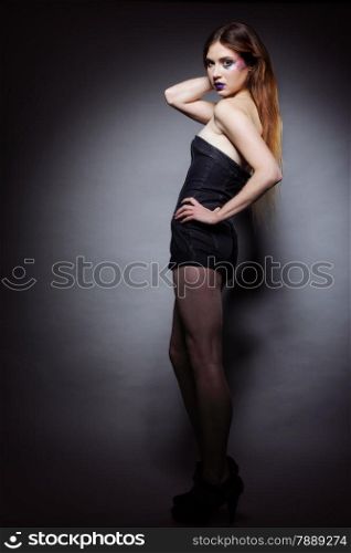 Full length woman straight long hair make-up posing in studio dark background