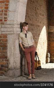 Full length young handsome man fashion model casual style with bag on street of old town Gdansk Poland Europe