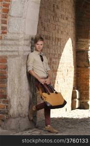 Full length young handsome man fashion model casual style with bag on street of old town Gdansk Poland Europe