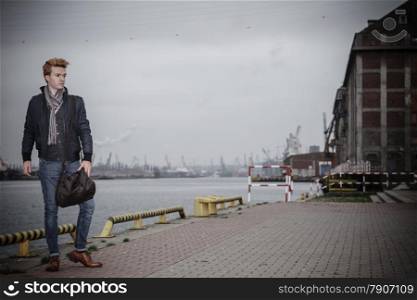 Full length young handsome man fashion model casual style with bag on street urban industrial background