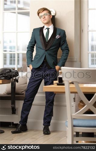 Full length young handsome stylish man fashion model posing in trendy cafe /restaurant with bag