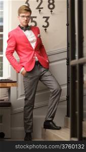 Full length young handsome stylish man fashion model wearning bright red jacket and bow tie posing indoor