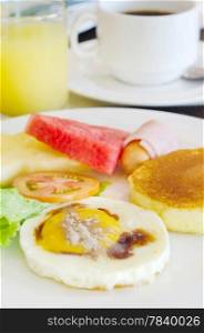 full meal for breakfast ( pancake , fried egg , ham and sausage , fresh vegetable and fruits , hot coffee and juice )