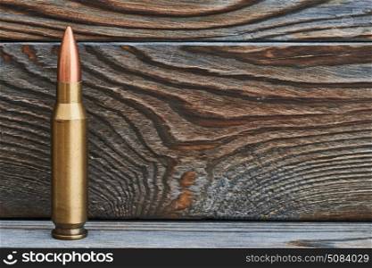 Full metal jacket bullet. Full metal jacket bullet on wooden background with copy space