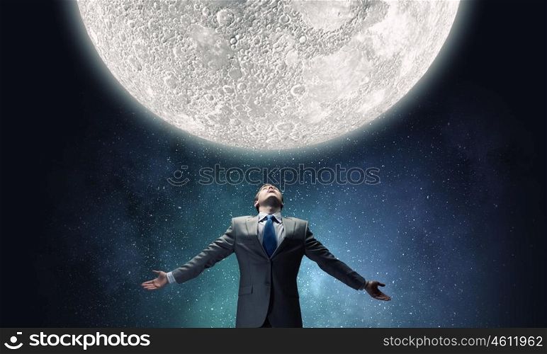 Full moon. Businessman with hands spread apart looking at moon above