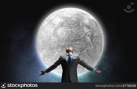 Full moon. Businessman with hands spread apart looking at moon above