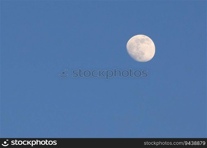 Full moon in clear dark blue evening sky with copy space