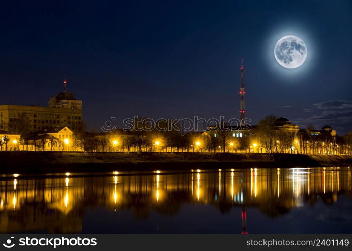 Full moon over the city. Night landscape. Lantern lights are reflected in the water. Supermoon.. Full moon over the city. Night landscape. Lantern lights are reflected in water. Supermoon.