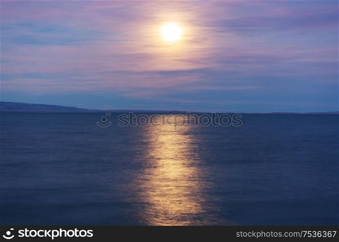 Full moon rising above mountain lake