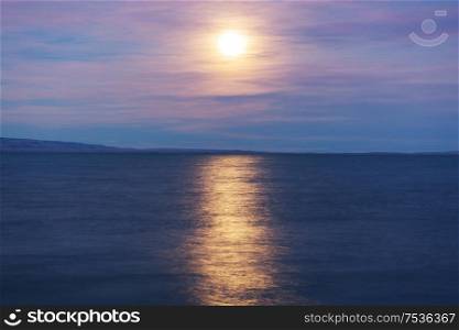 Full moon rising above mountain lake