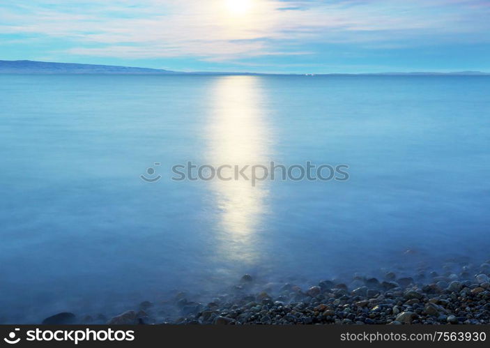 Full moon rising above mountain lake